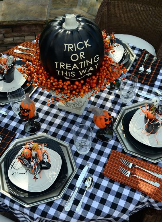 a blakc pumpkin with letters, berries on a vintage stand is ideal for a Halloween party