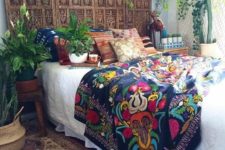 a boho wooden carved headboard made of a wooden screen is a stylish idea for a free-spirited bedroom