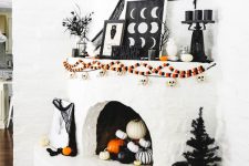 a bold Halloween mantel with colorful garlands, letters, spiderweb, black candles, branches and black and white pumpkins