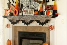 a bright and fun Halloween mantel with a spiderweb, marquee letters, bats, pumpkins and candy corns is cool