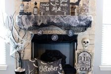 a chic Halloween mantel with paper bats, spiderweb, apothecary bottles, skulls and black pillows and a skeleton