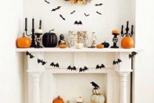 a fantastic fall and Halloween mantel with bats, a bat garland, black and orange pumpkins and black candles