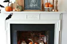a farmhouse Halloween mantel with bats, cutting boards, candles in wooden candleholders, pumpkins all over and a witch hat sign
