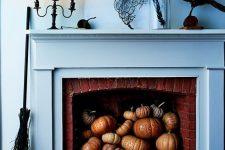 a moody Halloween mantel with a coral, a feather in a jar, a bird, black candles and lots of pumpkins in the fireplace