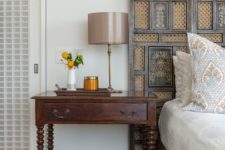 a refined carved wooden screen headboard matches the bed and bedside table and brings a refined vintage touch