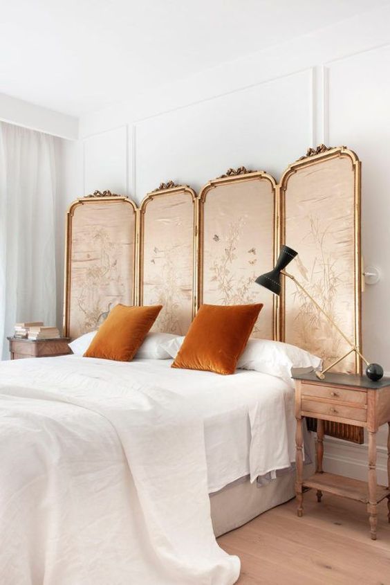 a refined fabric upholstered headboard is a chic idea and rust-colored pillows add to it