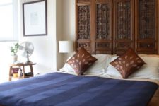 a rich stained carved wooden headboard that matches the bed and makes a bold and chic statement here