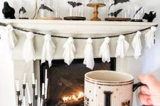 a stylish Halloween mantel with a ghost garland, bats in cloches and blackbirds is an elegant piece