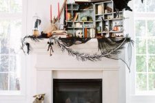 a whimsy Halloween mantel with colorful candles, a box with candles, skulls and apothecary bottles, a cage and faux birds