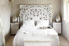 a white carved wooden headboard adds to the boho look of the beautiful bedroom