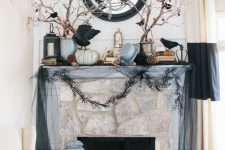 an elegant Halloween mantel with blackbirds, branches with them, a top hat, pumpkins, antlers and lotus