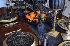 black and gold pumpkins on stands, orange pumpkins on the table and a spiderweb table runner for Halloween