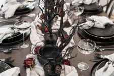 black planters with black branches, black cauldrons, dried roses, grey candles for a Halloween tablescape