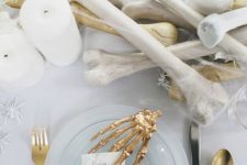 bones, candles, spiders and gold cutlery and a skeleton hand for styling your white and gold Halloween