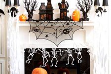 bright Halloween mantel decor with black houses, scary trees, skeletons, bats and cutout pumpkins on the floor