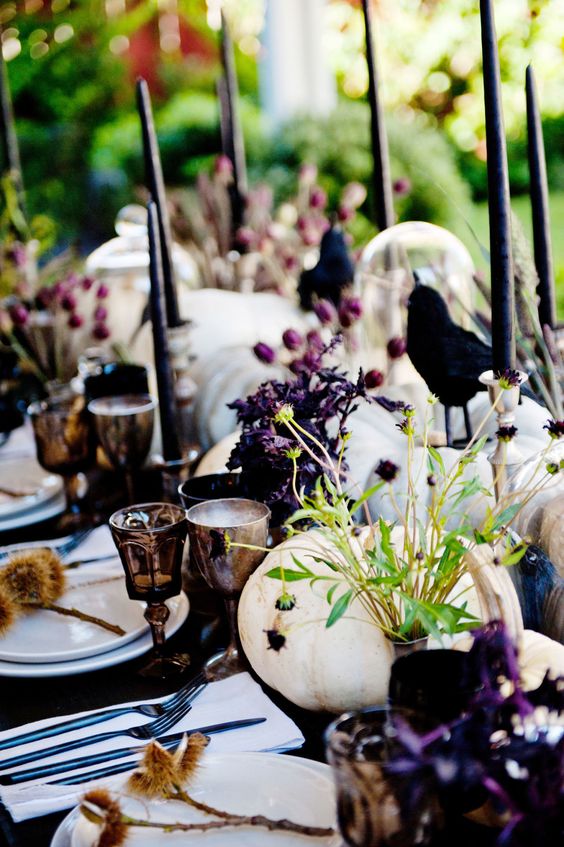 white pumpkins, berries, purple blooms, black candles and crows are ideal to decorate your Halloween table