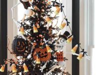 a black Halloween tree with candy corn garlands, bones, glitter jack-o-lanterns and lights is a bold idea