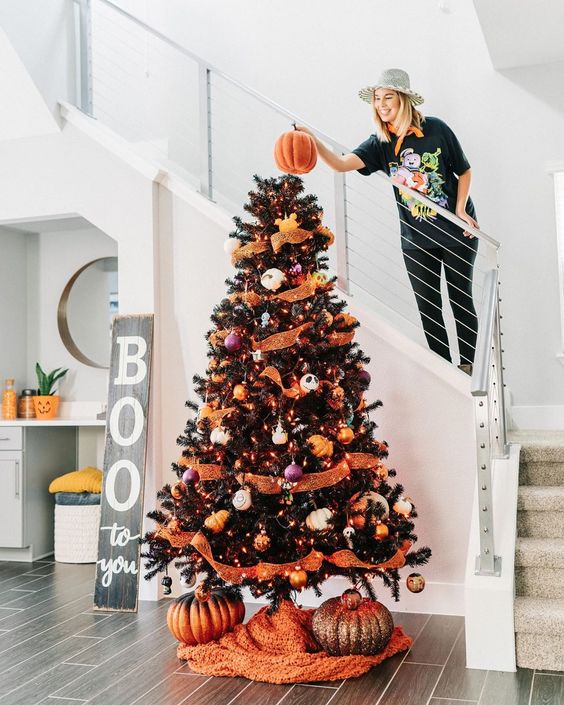 a black Halloween tree with orange ribbons, pumpkins, purple and orange ornaments and glitter pumpkins under it
