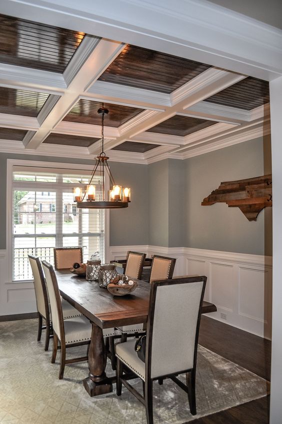 a catchy and contrasting ceiling in white and stained wood plus matching furniture make the space very stylish