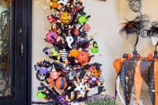 a haunted Halloween tree in black decorated with colorful ornaments, pumpkins, skulls and bats plus candy corns