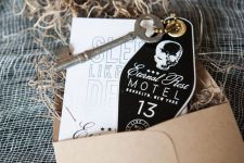 a kraft paper envelope, black and white coffin-shaped invites and a vintage key for a Halloween party