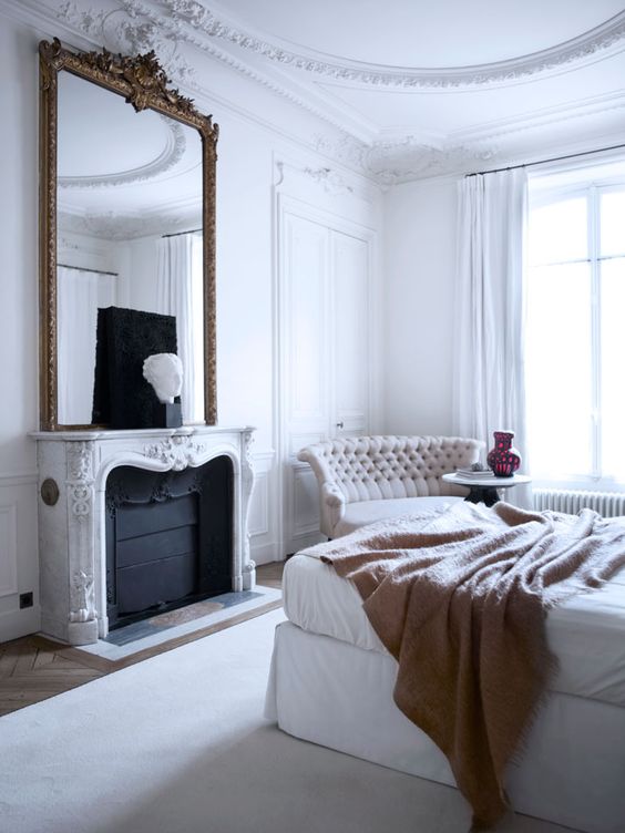 a refined bedroom with vintage molding, a molded fireplace and a mirror frame that echoes with sophisticated furniture