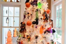 a white Halloween tree with colorful witch legs, hats, dolls and lights plus mini ghosts and bells
