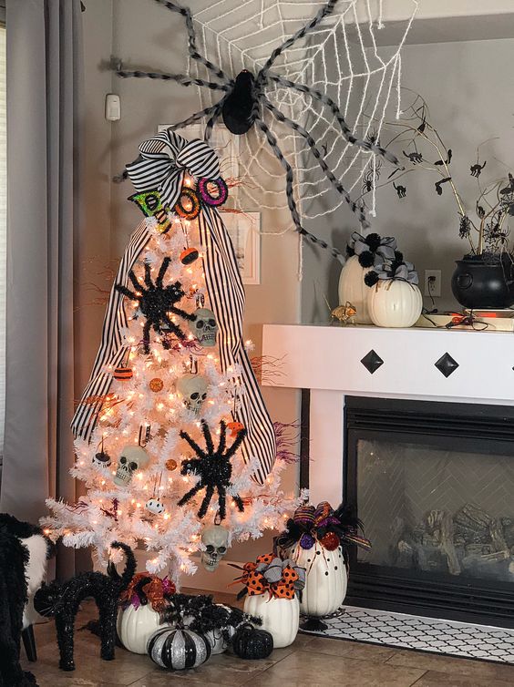 a white Halloween tree with skulls, spiders, lights and mini pumpkins plus a giant web over the tree