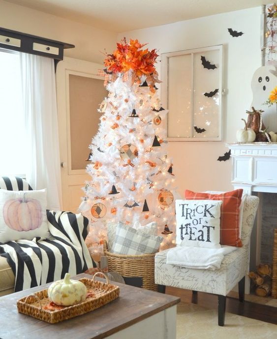 an airy Halloween tree in white, with paper ornaments, bats, witch hats and bold fall leaves on top