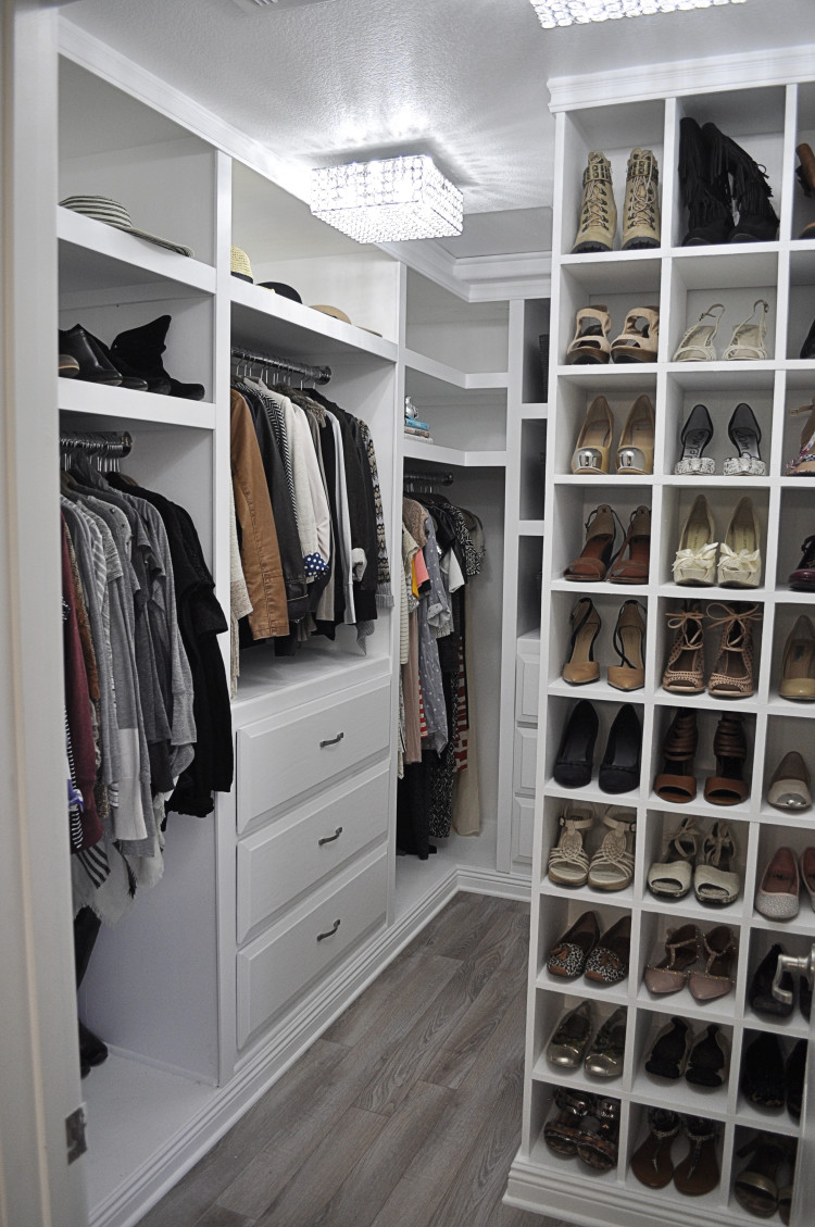 very well organized walk in closet with white cabinets and storage units