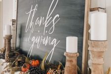 a beautiful rustic Thanksgiving mantel with faux pumpkins, pinecones, berries, faux leaves and greenery, candles and a large sign