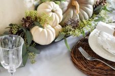 a bowl with eucalyptus, white and green pumpkins and pinecones is a classic Thanksgiving centerpiece