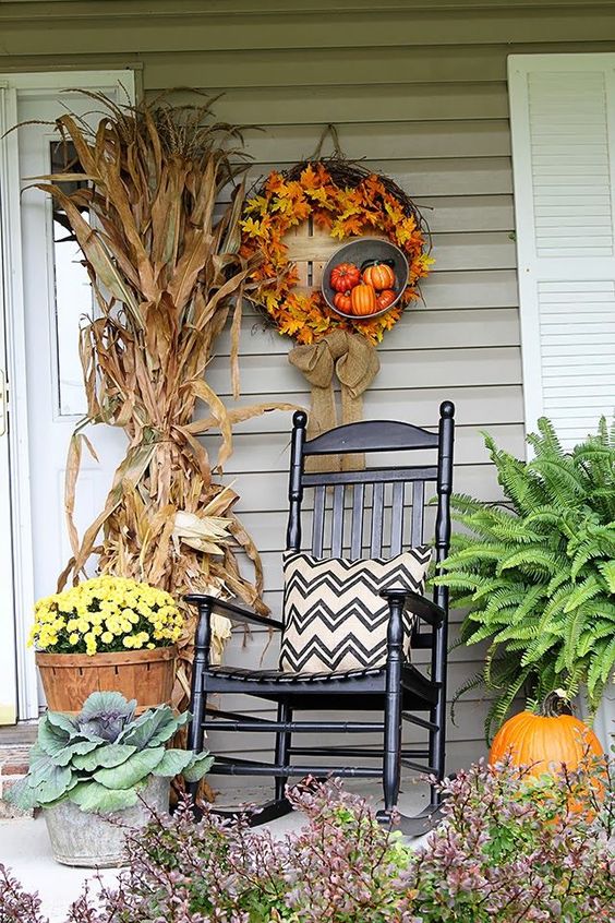 a bright and simple fall porch with a husk bundle, potted blooms, cabbage and ferns, pumpkins and a fall leaf wreath