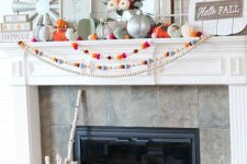 a bright fall or Thanksgiving mantel with colorful felt garlands, bright and metallic pumpkins, felt leaves and a sign