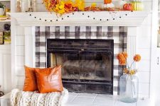 a colorful Thanksgiving mantel with bright stacked pumpkins, a pompom garland, bright faux leaves, bright faux pumpkins and gourds