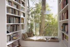 a contemporary windowsill nook with a bench with pillows and cushions and lots of bookshelves taking each wall