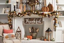 a cool Thanksgiving mantel with faux pumpkins, leaves and wooden pumpkins, firewood, crochet pumpkins and candles