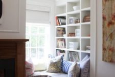 a corner windowsill reading nook with built-in shelves and colorful pillows is super cozy