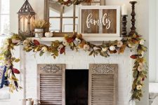 a fall leaf and pumpkins wreath and garland, candles and lanterns plus a rustic sign