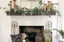 a farmhouse mantel with greenery, candles in wooden candleholders, faux pumpkins, a wood slice wreath with pumpkins and pumpkins by the fireplace