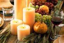 a harvest centerpiece of a wooden board, wheat, grapes, gourds, candles is a beautiful Thanksgiving piece