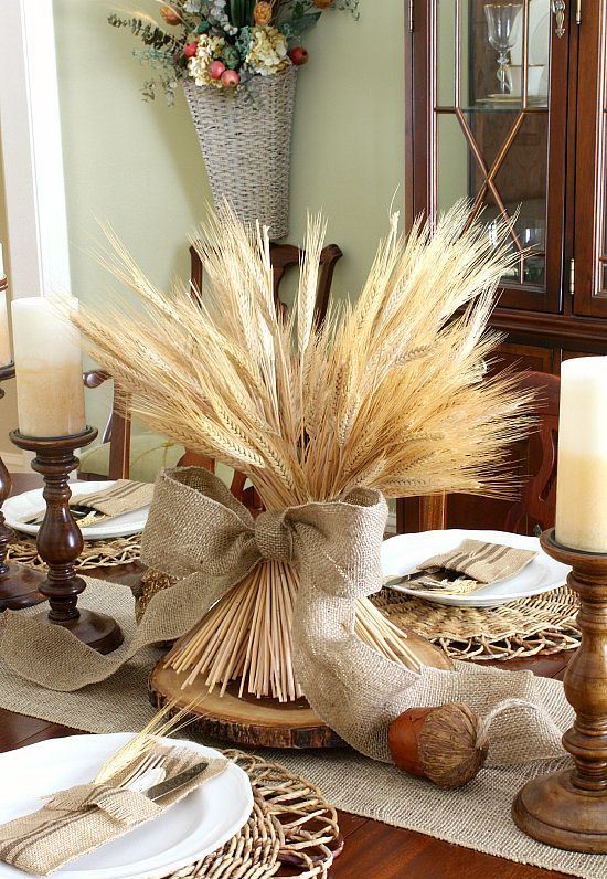 a large bundle of wheat with a giant burlap bow and large acorns and candles make up a chic Thanksgiving centerpiece