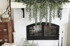 a natural Thanksgiving mantel with fresh cascading greenery, white pumpkins and a white bread bowl