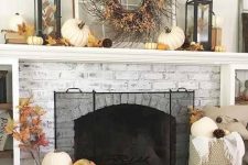 a rustic mantel with faux leaves and pumpkins, a vine wreath with leaves and candles with leaves for Thanksgiving