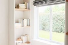 a small contemporary reading nook by the window, with built-in bookshelves and dark shades is a veyr cozy space