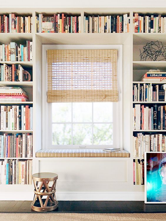 a small traditional reading nook with an upholstered bench and built in shelves all over the bench