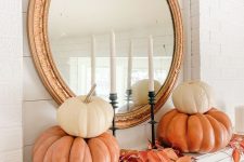 a stylish vintage-inspired mantel with bright leaves and stacked pumpkins plus a gold frame mirror