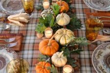 a traditional Thanksgiving centerpiece of oak leaves and acorns, candles and faux and natural pumpkins