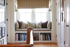 a windowsill reading nook with an upholstered bench and some built-in shelves under it looks cute and cozy
