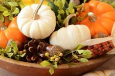 a wooden bowl filled with pumpkins, corn, pinecones, berries and greenery is a great rustic decoration for the fall